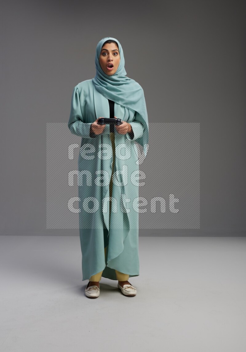 Saudi Woman wearing Abaya standing Playing Games on Gray background