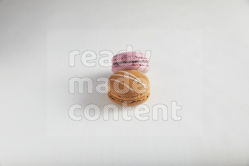 45º Shot of of two assorted Brown Irish Cream, and Purple Strawberry macarons on white background