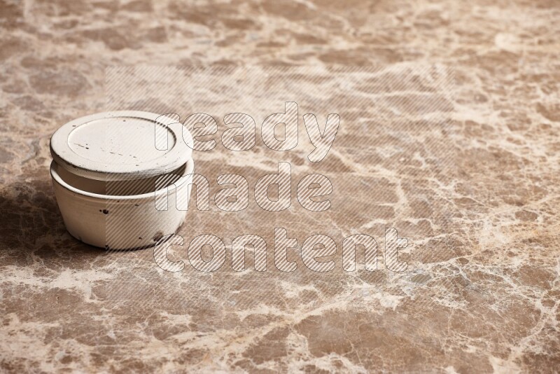 A white pottery bowl on beige marble background
