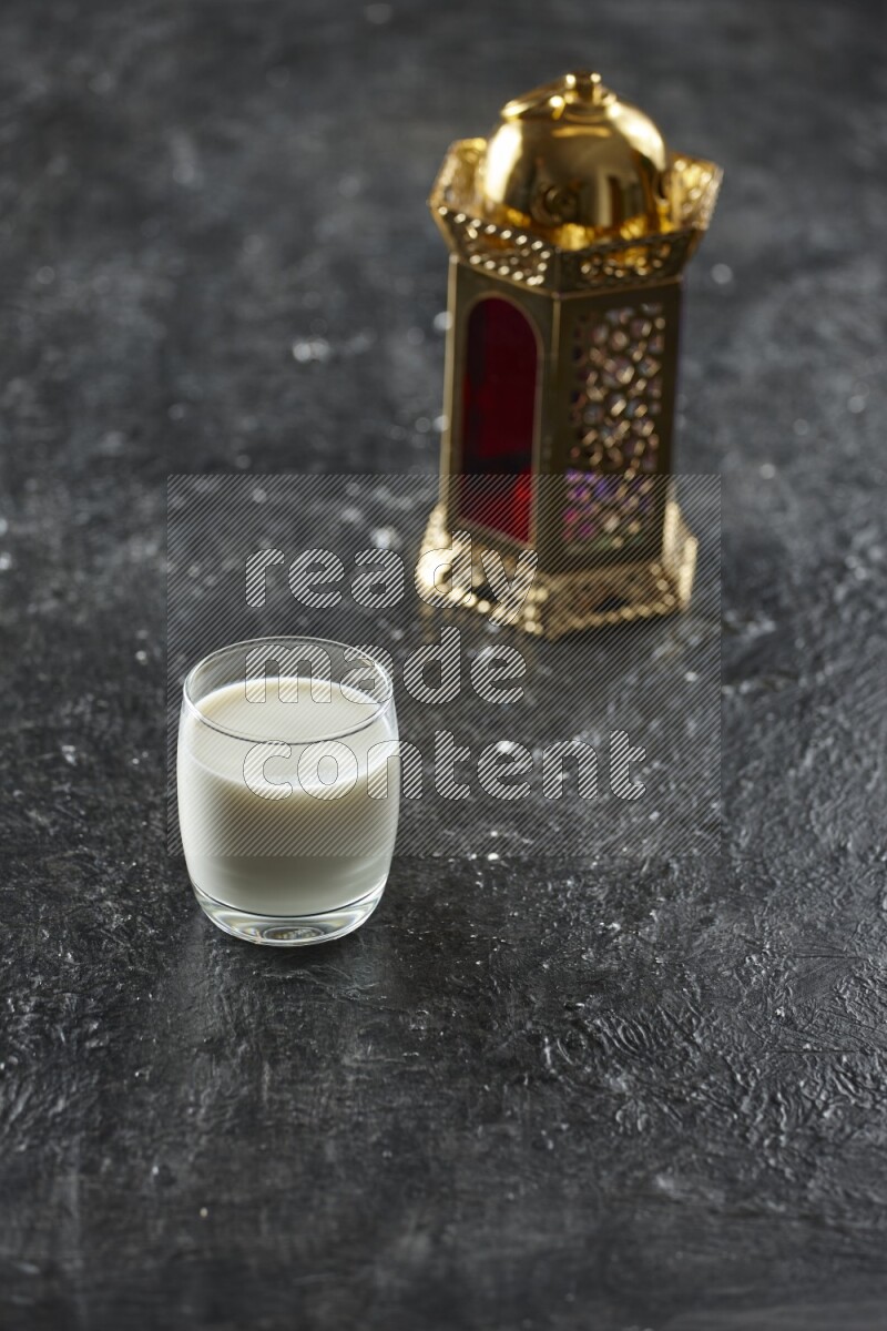A golden lantern with different drinks, dates, nuts, prayer beads and quran on textured black background