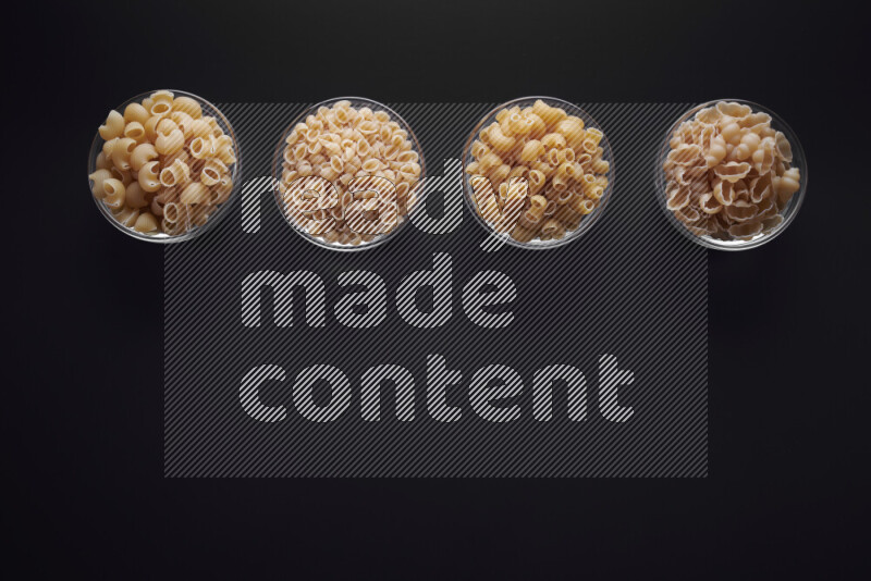 أنواع مختلفة من المعكرونة في وعاء زجاجي علي خلفية سوداء