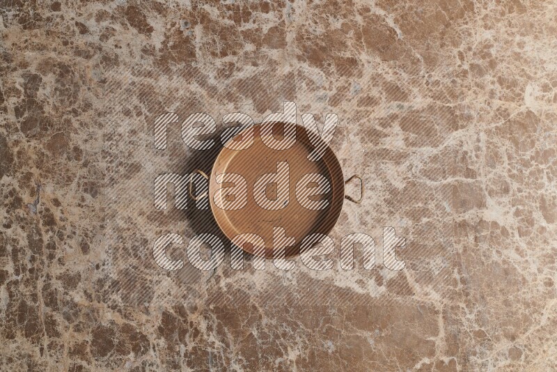 A small copper pan on beige marble background