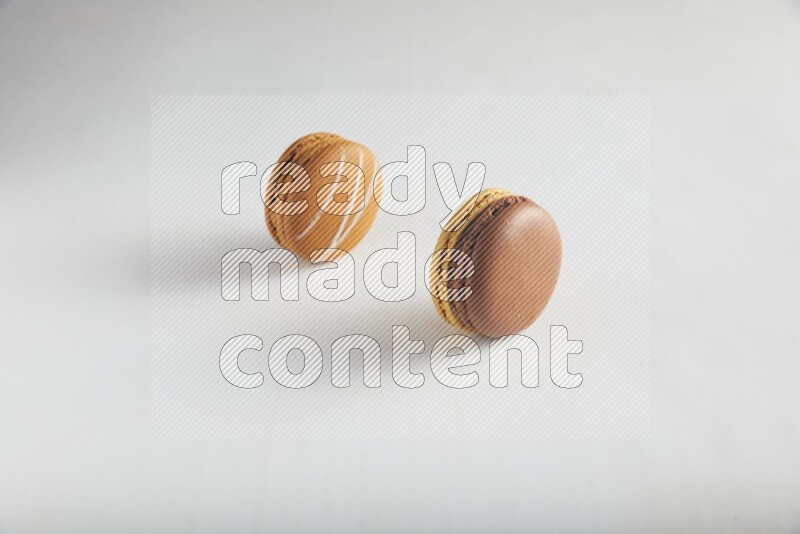 45º Shot of of two assorted Brown Irish Cream, and Yellow, and Brown Chai Latte macarons on white background