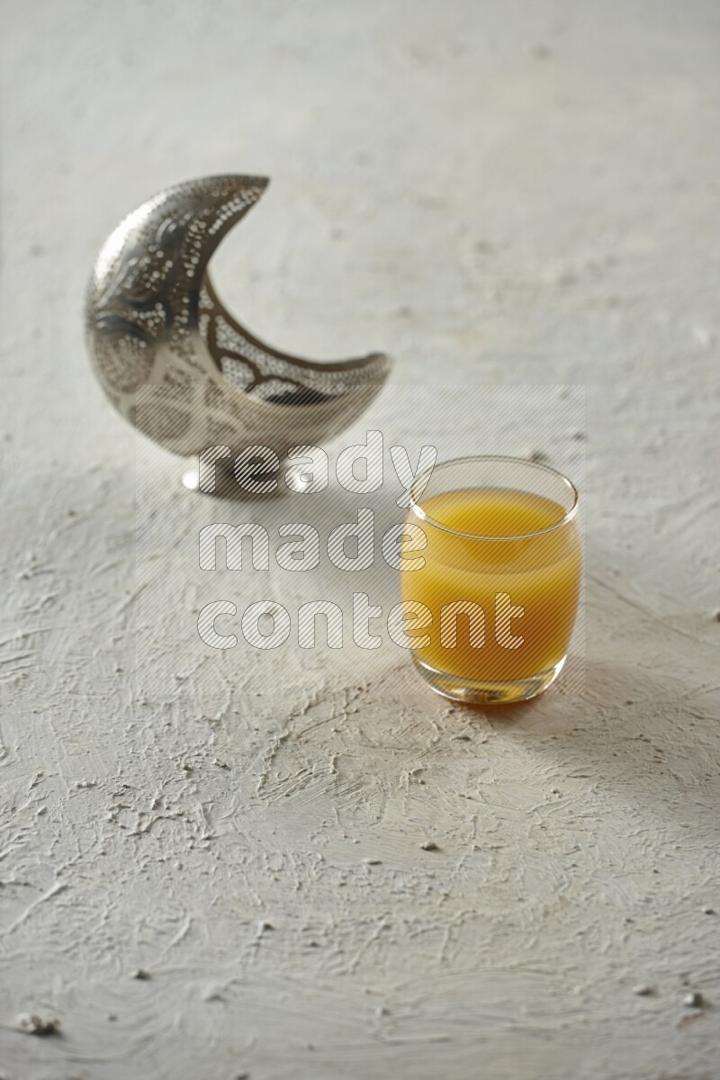 A silver lantern with different drinks, dates, nuts, prayer beads and quran on textured white background