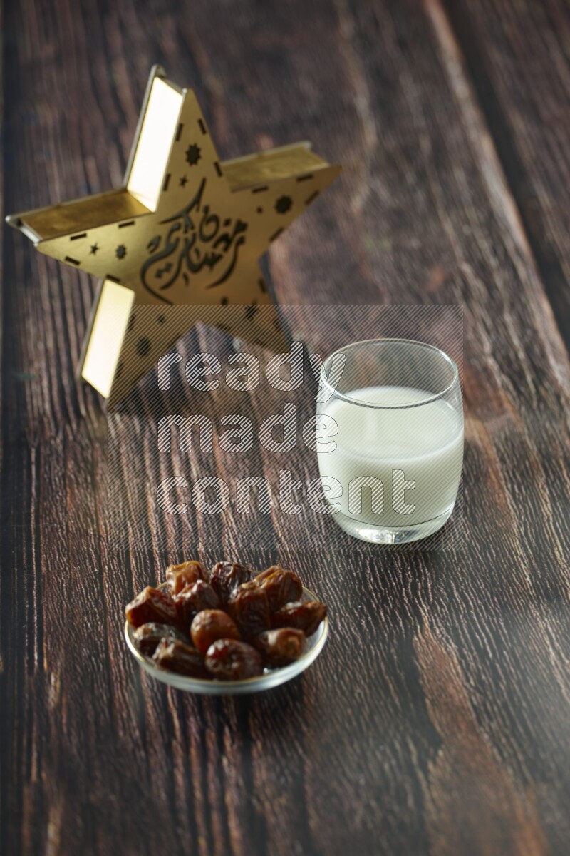 A wooden golden star lantern with different drinks, dates, nuts, prayer beads and quran on brown wooden background