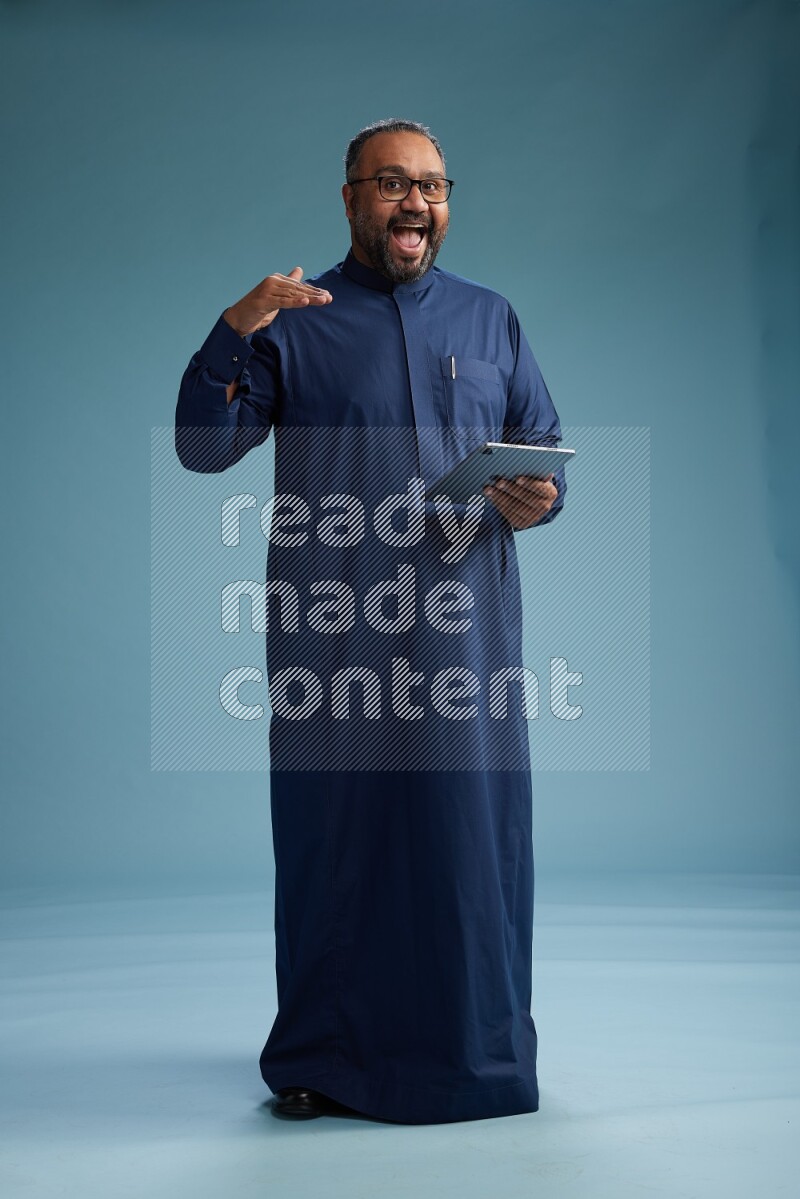 Saudi Man without shimag Standing working on tablet on blue background