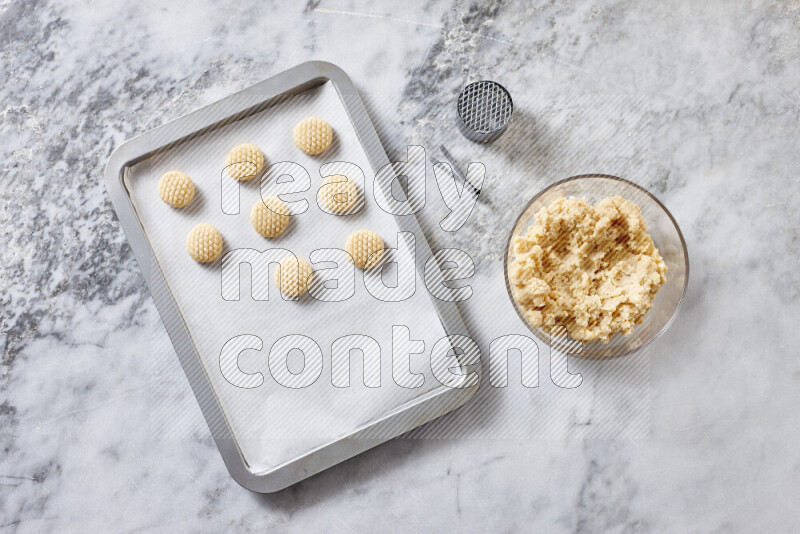 كحك خطوة بخطوة بمكوناته سمن، سكر، دقيق، سمسم، خميرة، ماء ونكهة الكحك على خلفية رخام رمادي