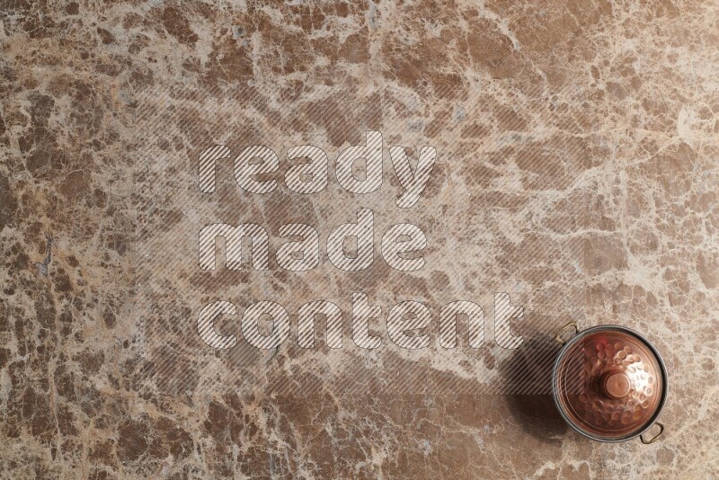 A small copper pot on beige marble background