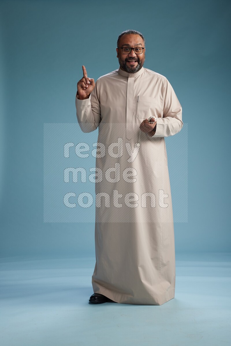 Saudi Man without shimag Standing Interacting with the camera on blue background