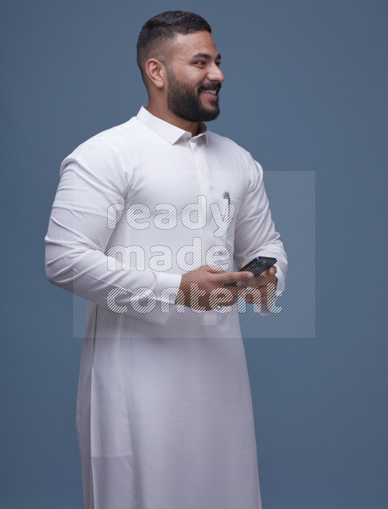 A man Texting on Blue Background wearing Saudi Thob