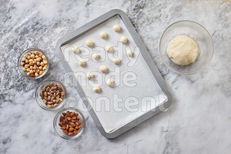 Ghoriba step by step with its ingredient, flour, powdered sugar, ghee and nuts on grey marble background