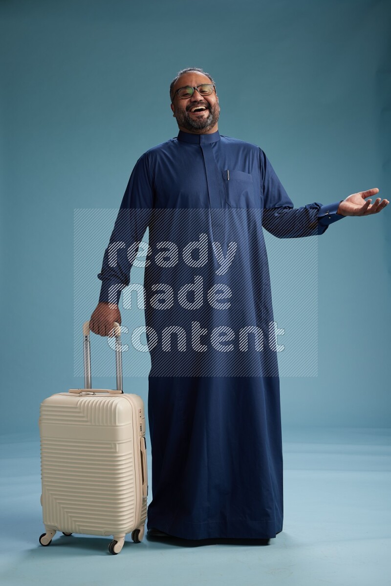 Saudi Man without shimag Standing pulling travel bag on blue background