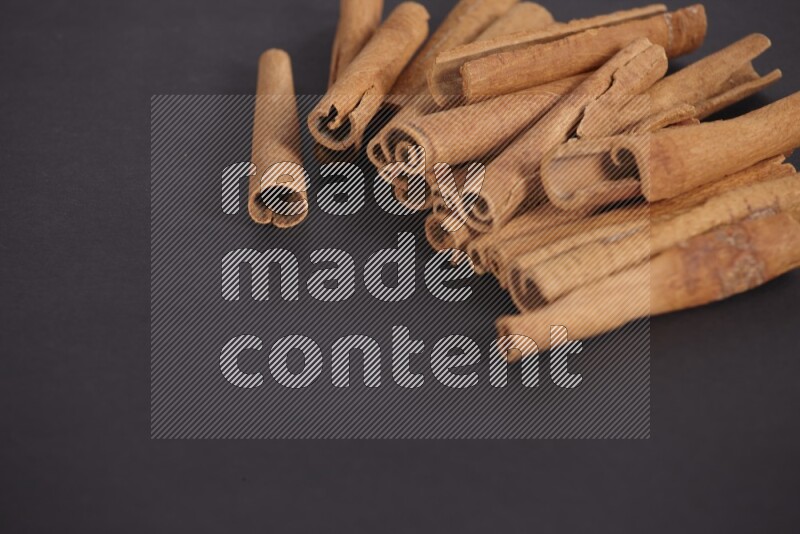 Cinnamon sticks stacked on black flooring