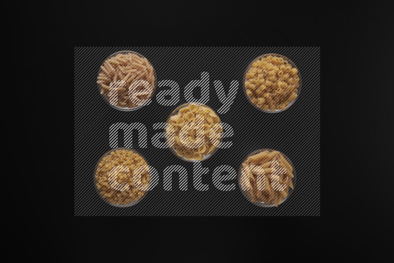 أنواع مختلفة من المعكرونة في أوعية زجاجية علي خلفية سوداء