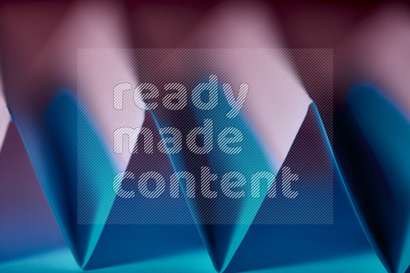 صورة مجردة مقربة تظهر طيات ورقية هندسية حادة بتدرجات اللون الأزرق والأحمر