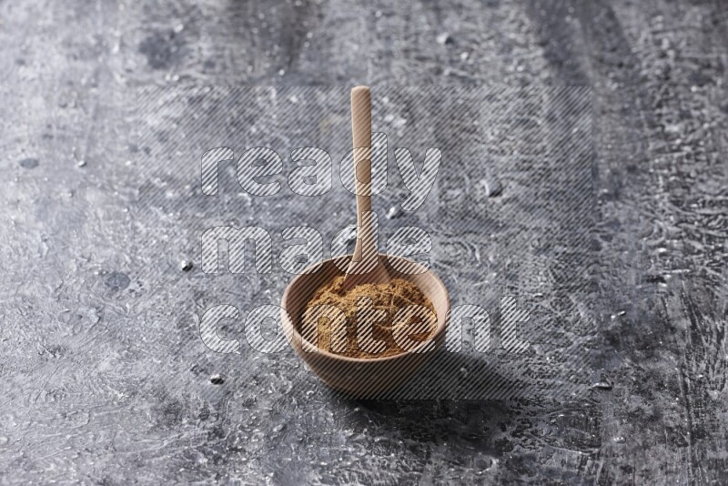Wooden bowl full of cinnamon powder with a wooden spoon on a textured black background in different angles