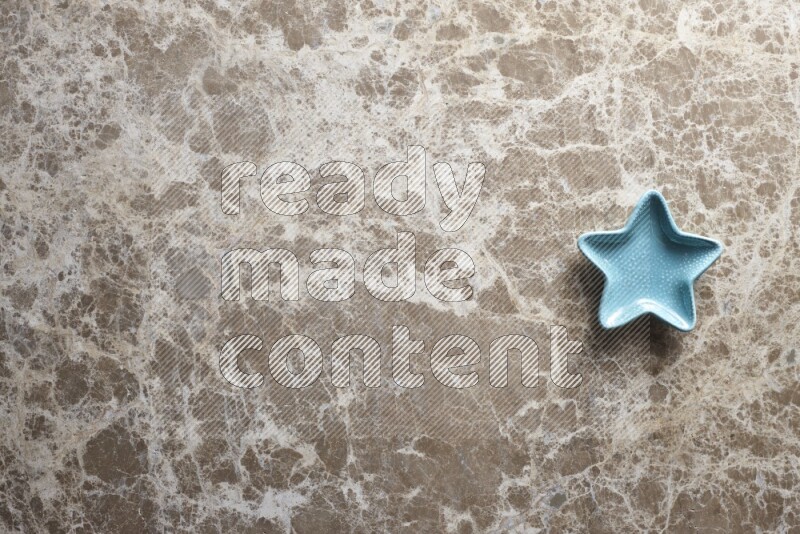 A colored pottery star plate on beige marble background