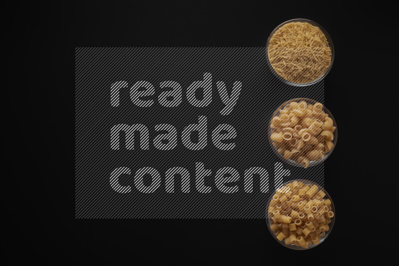 Different pasta types in 3 glass bowls on black background