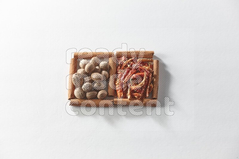 2 squares of cinnamon sticks full of dried red chilis and nutmegs on white flooring