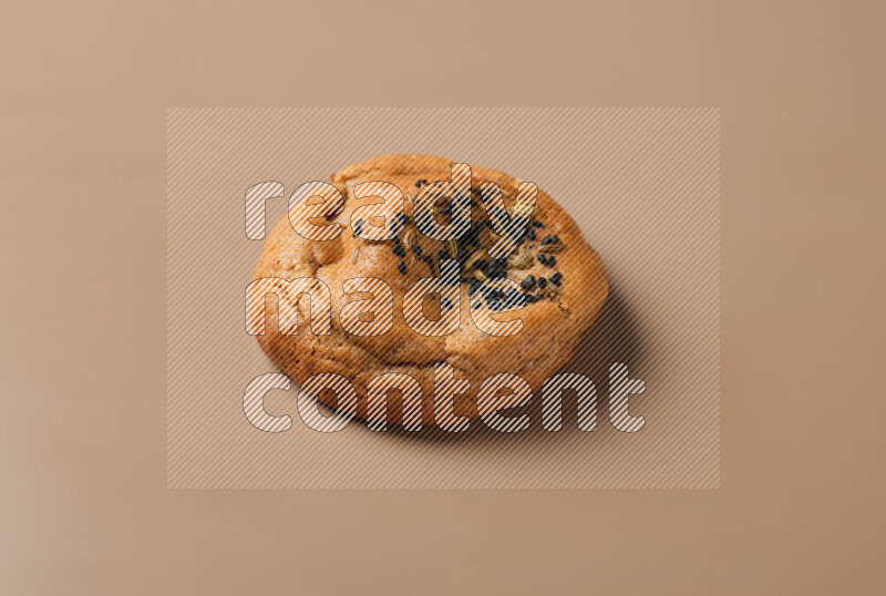 a whole Hasawi cookie with grains on a brown background