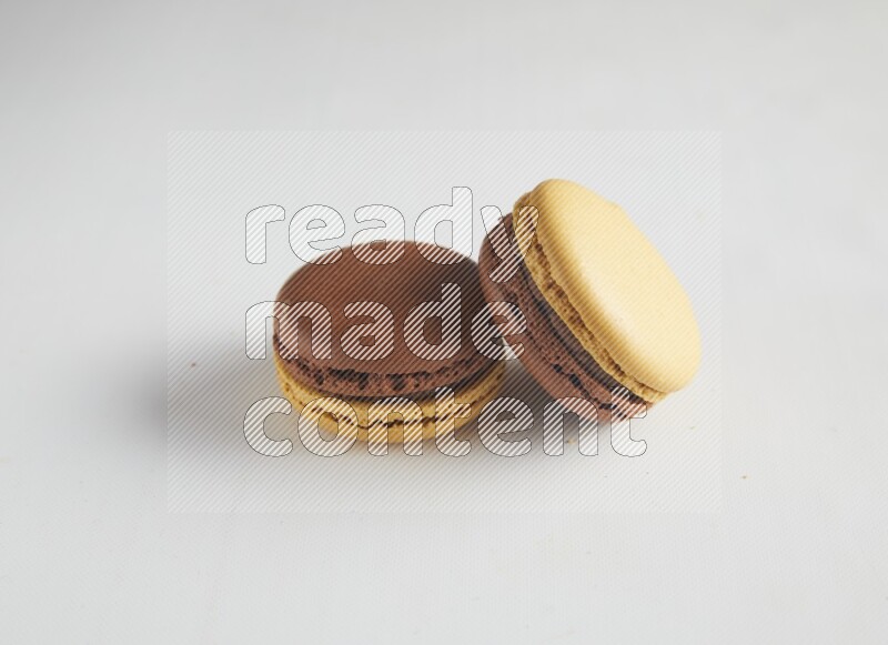 45º Shot of two Yellow and Brown Chai Latte macarons on white background