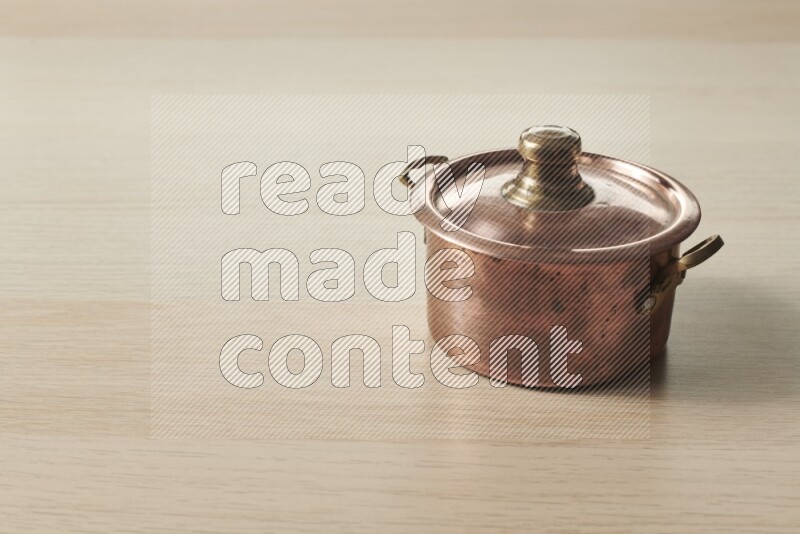 A small copper pot on light wooden background