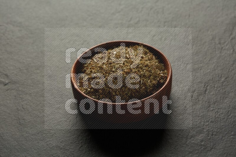 wooden round sauce bowl filled with herbs on grey textured countertop