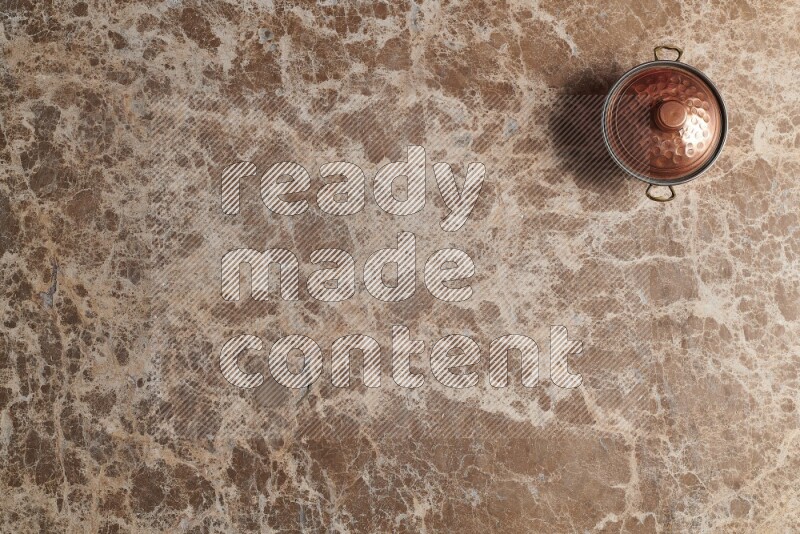 A small copper pot on beige marble background