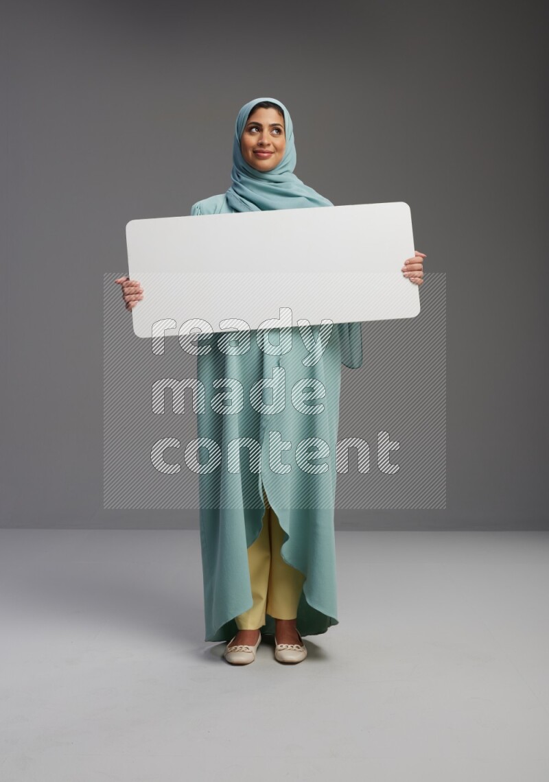 Saudi Woman wearing Abaya standing holding board on Gray background