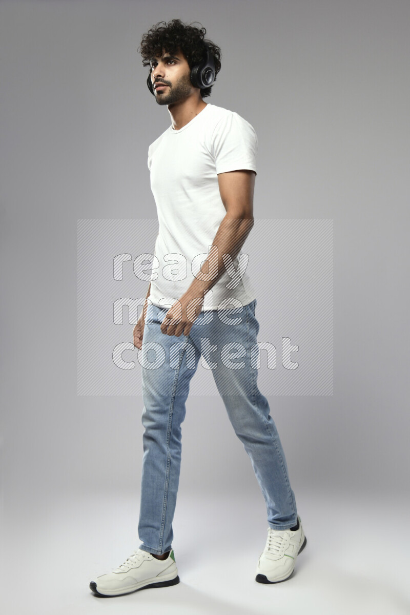 A man wearing casual standing and putting on headphones on white background