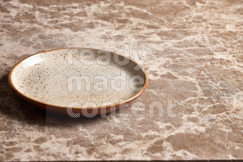 A multicolored pottery plate on beige marble background