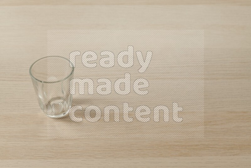 An empty glass cup on light wooden background