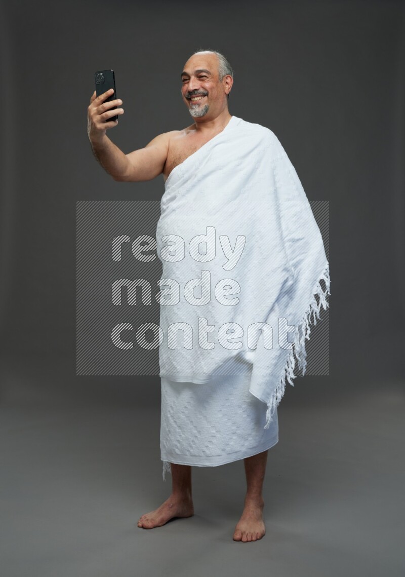 A man wearing Ehram Standing taking selfie on gray background