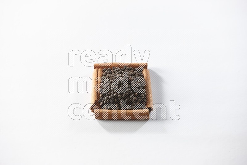 A single square of cinnamon sticks full of black pepper on white flooring
