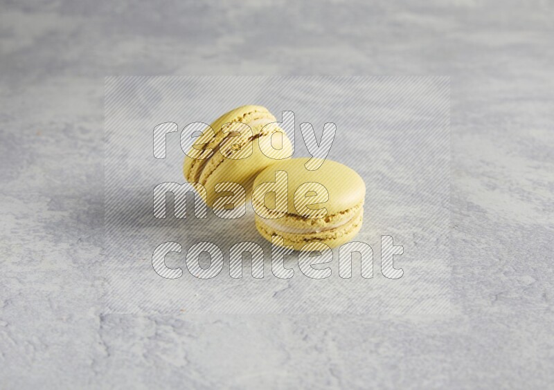 45º Shot of two Yellow Lime macarons  on white  marble background