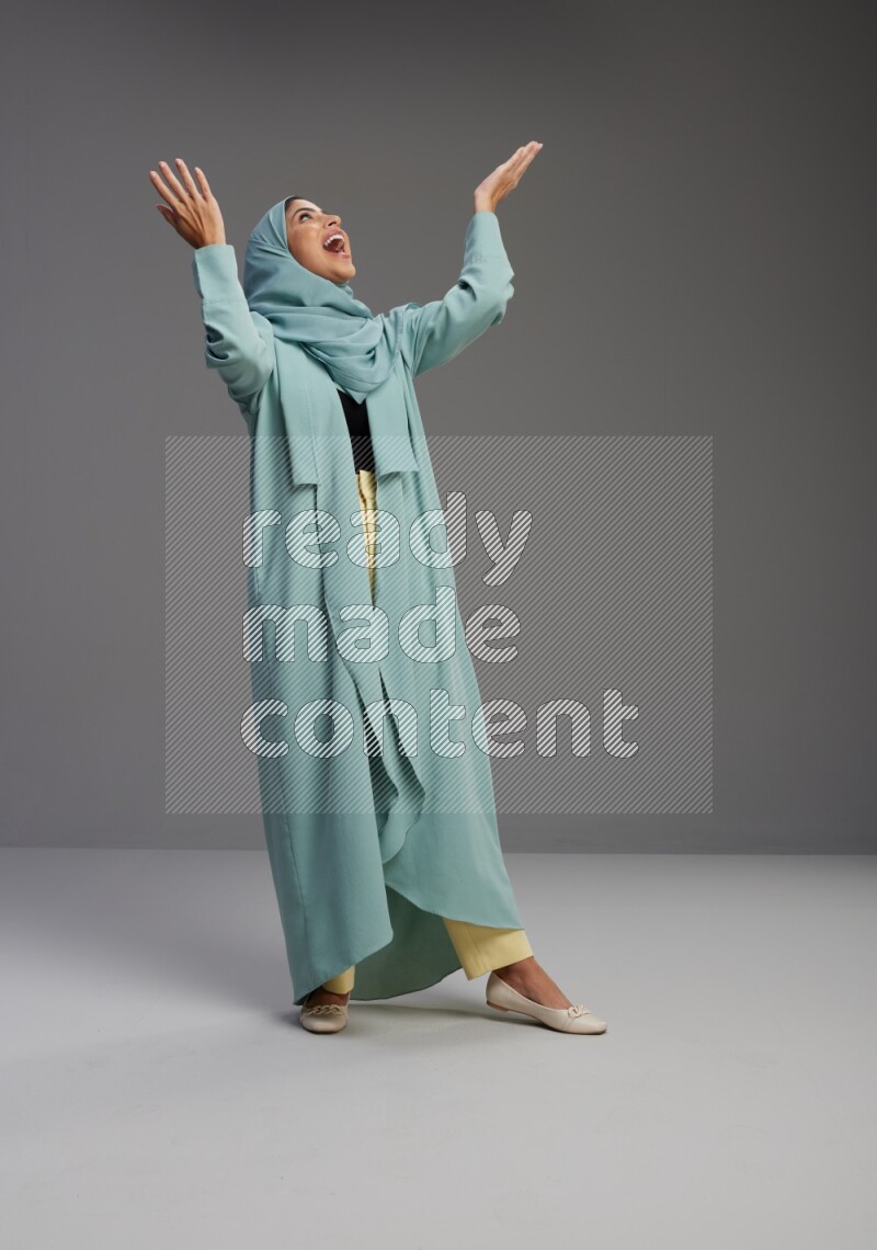 Saudi Woman wearing Abaya standing interacting with the camera on Gray background