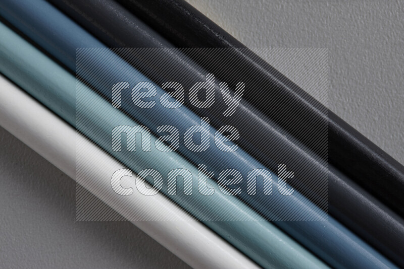 A collection of colored pencils arranged showcasing a gradient of white, grey and black hues on grey background