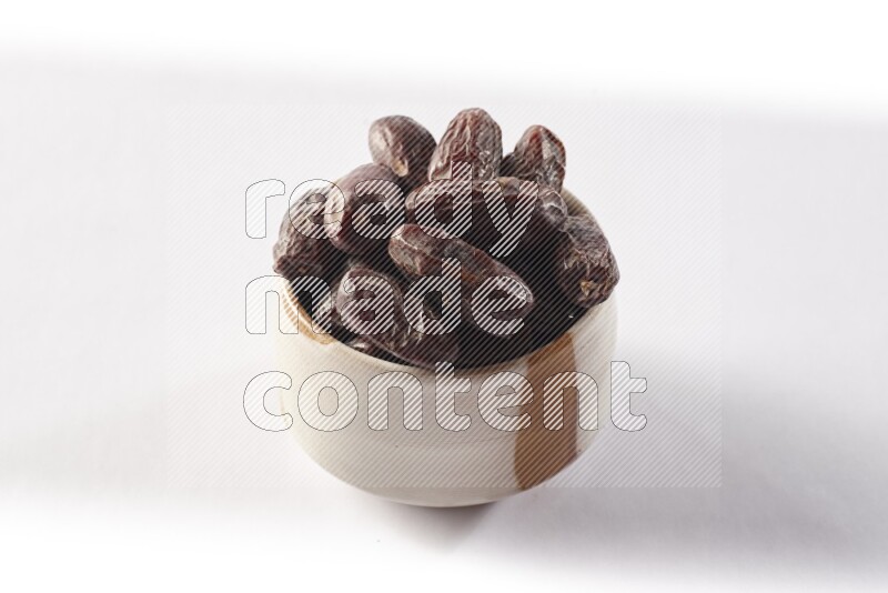 Dates in a beige pottery bowl on white background
