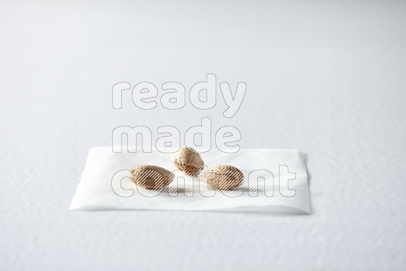 3 almonds on a piece of paper on a white background in different angles