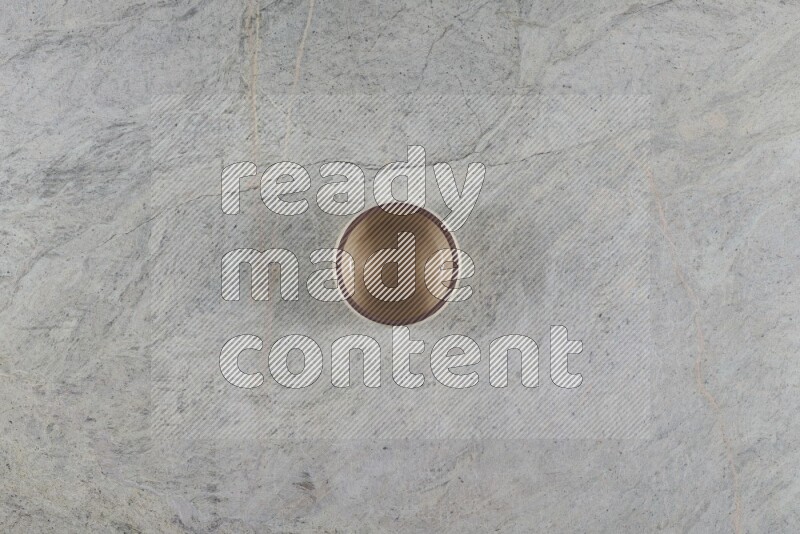 A small beige pottery bowl on grey marble background