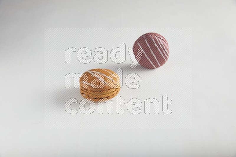 45º Shot of of two assorted Brown Irish Cream, and Red Poppy Flower macarons on white background