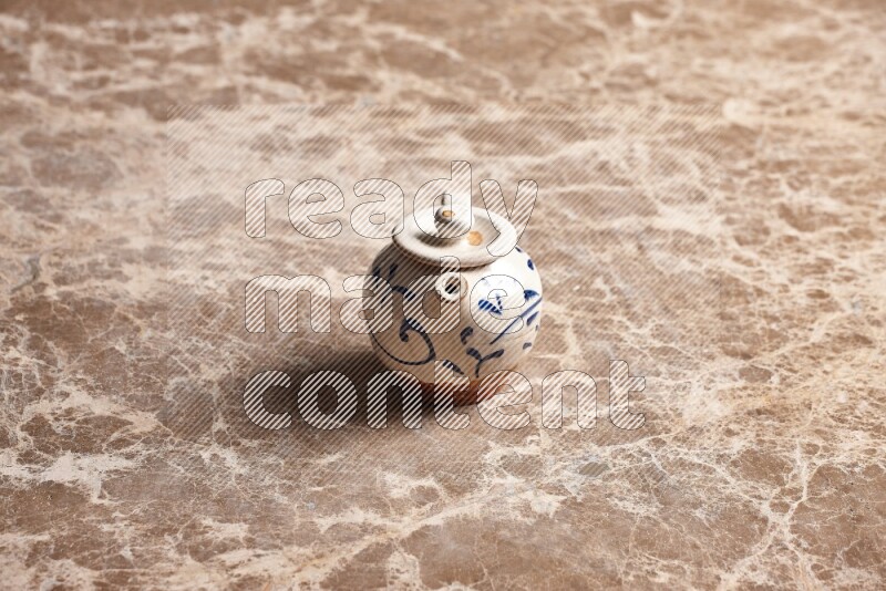 A pottery teapot on beige marble background