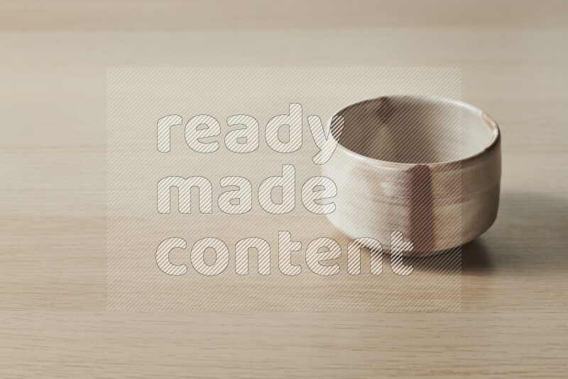 A beige pottery bowl on light wooden background