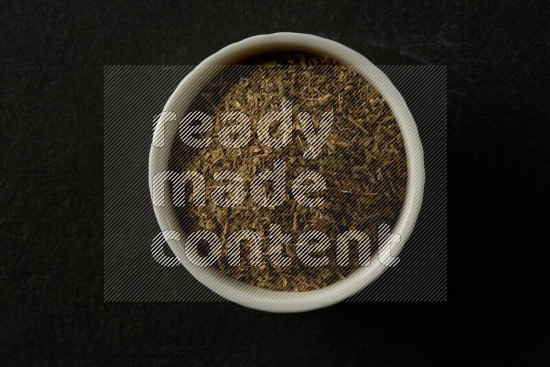 wooden round sauce bowl filled with herbs on grey textured countertop