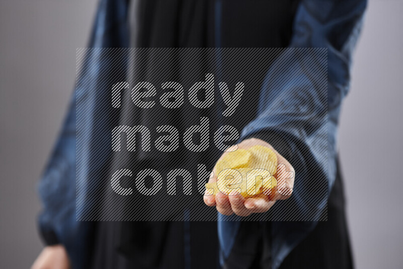 Woman in abaya holding different kinds of snacks in different positions