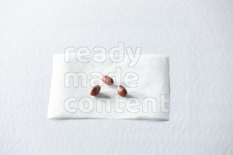 3 red skin peanuts on a piece of paper on a white background in different angles