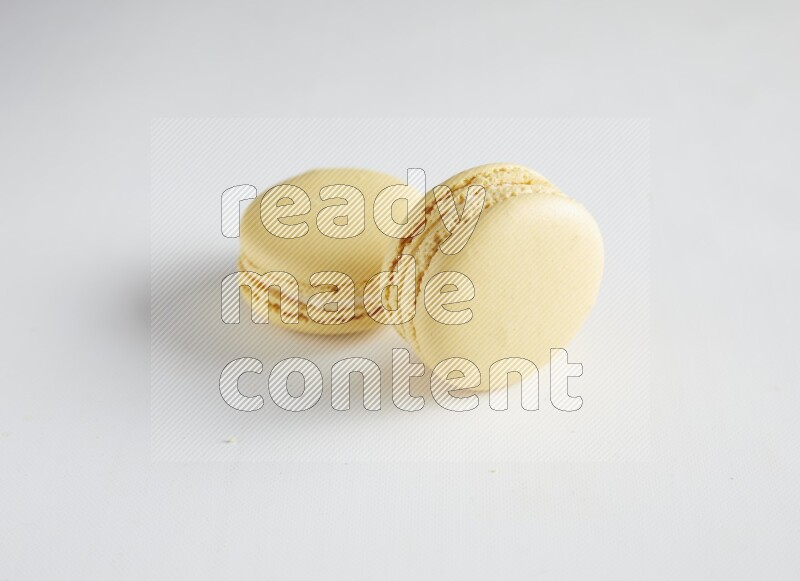 45º Shot of two Yellow Vanilla macarons on white background