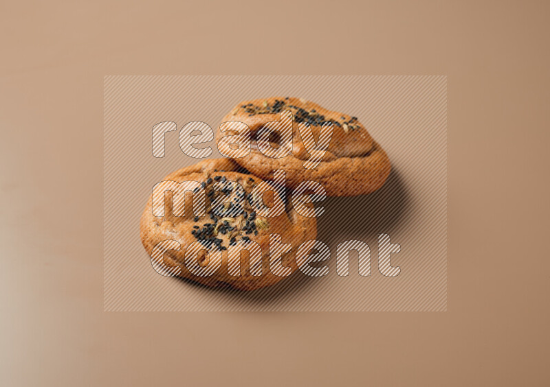 Two chocolate chip cookies on a brown background