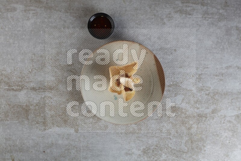 wonton cups with soy sauce ramkin on multi colored pottery on grey textured counter top