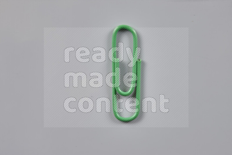 Green paper clips isolated on a grey background